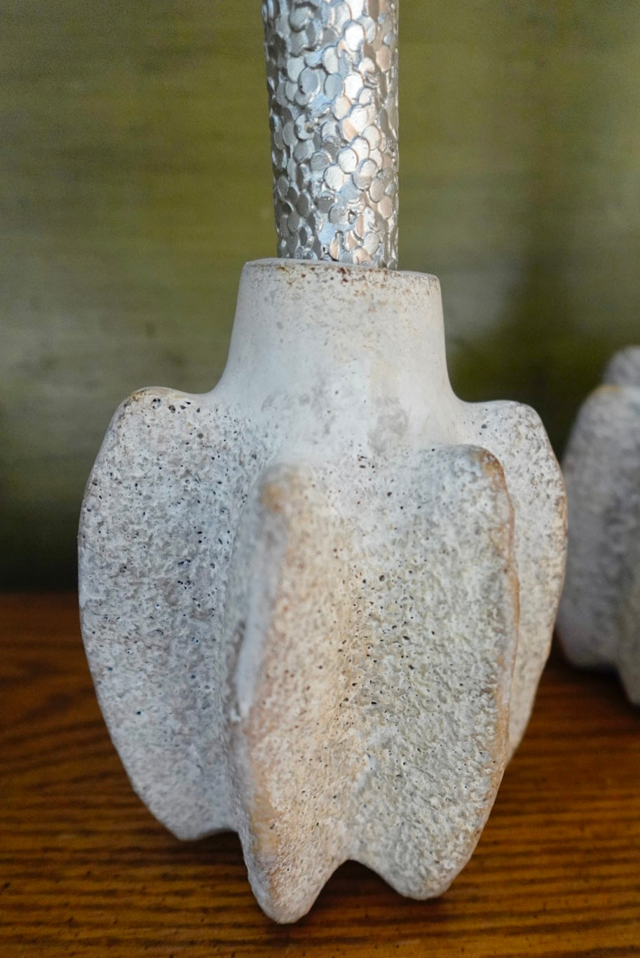 Close-up of a concrete or ceramic tool head with metallic handle on a wooden surface.