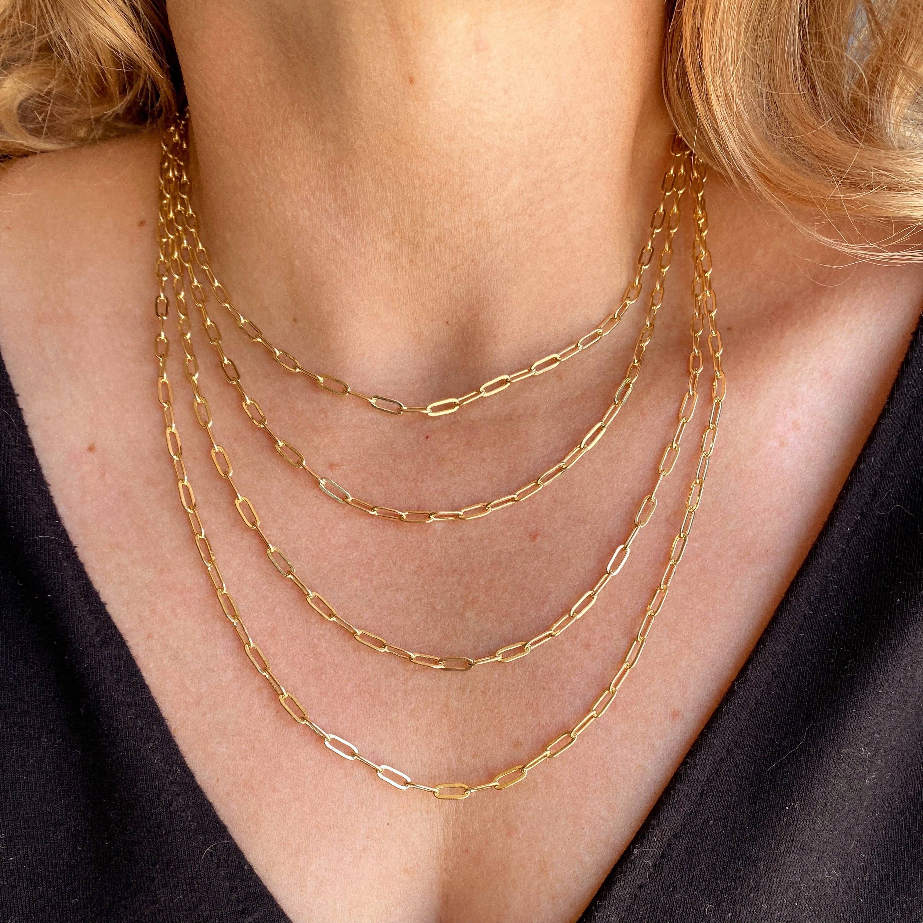 Gold chain necklaces on a person wearing a black top