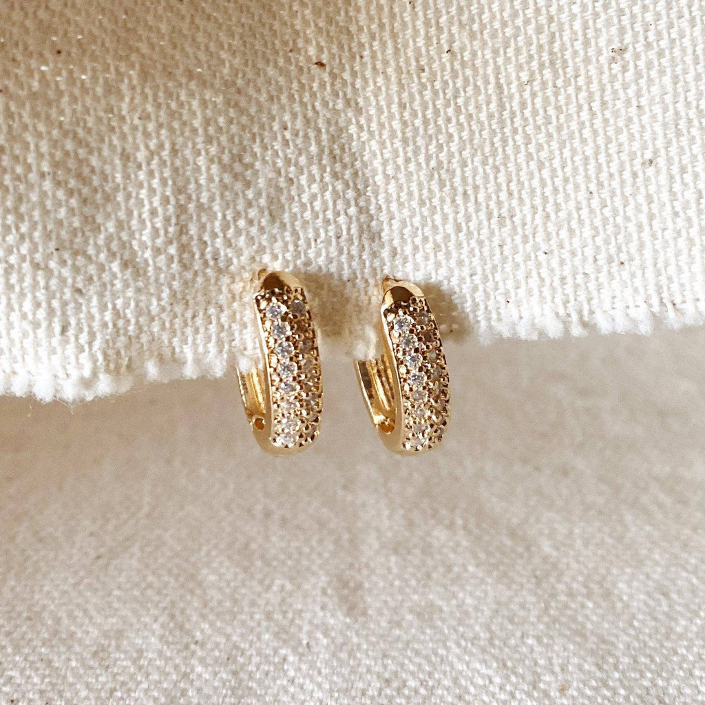 Gold hoop earrings on a textured beige surface