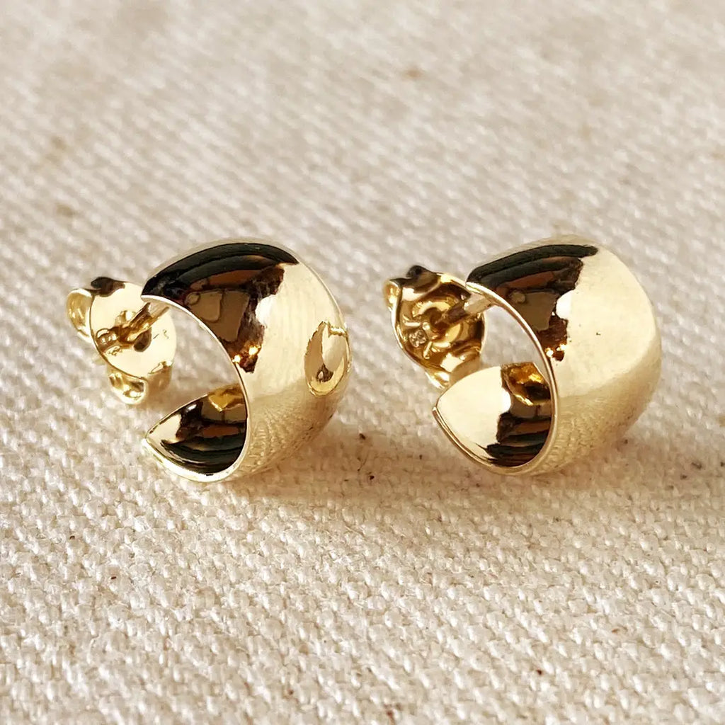 Pair of gold earrings on a textured beige surface