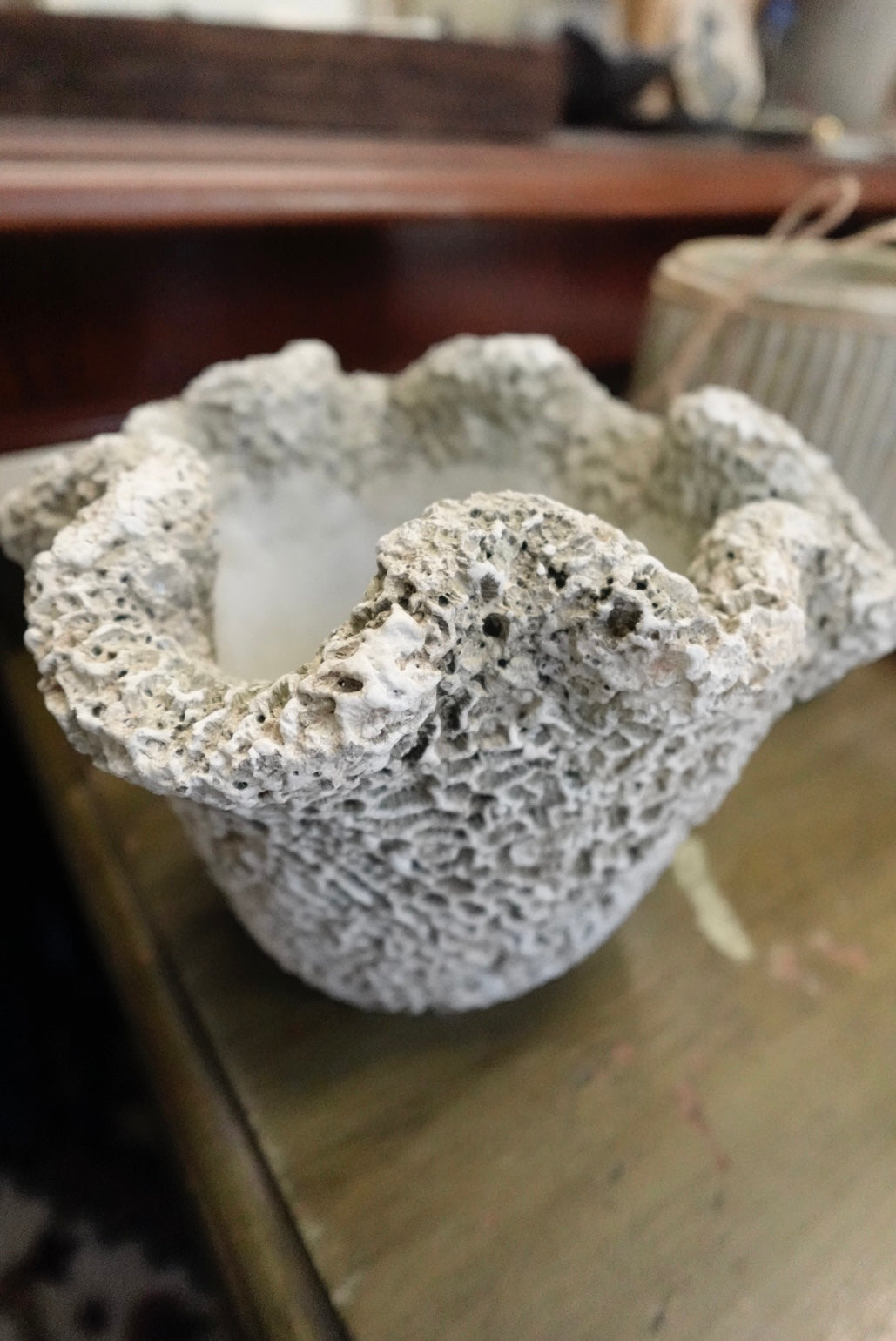 Candle in a textured stone holder on a wooden surface