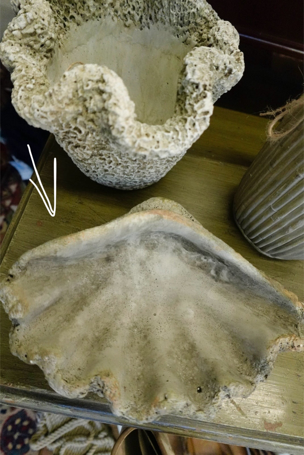 Close-up of a textured stone object on a wooden surface with a white vase in the background.