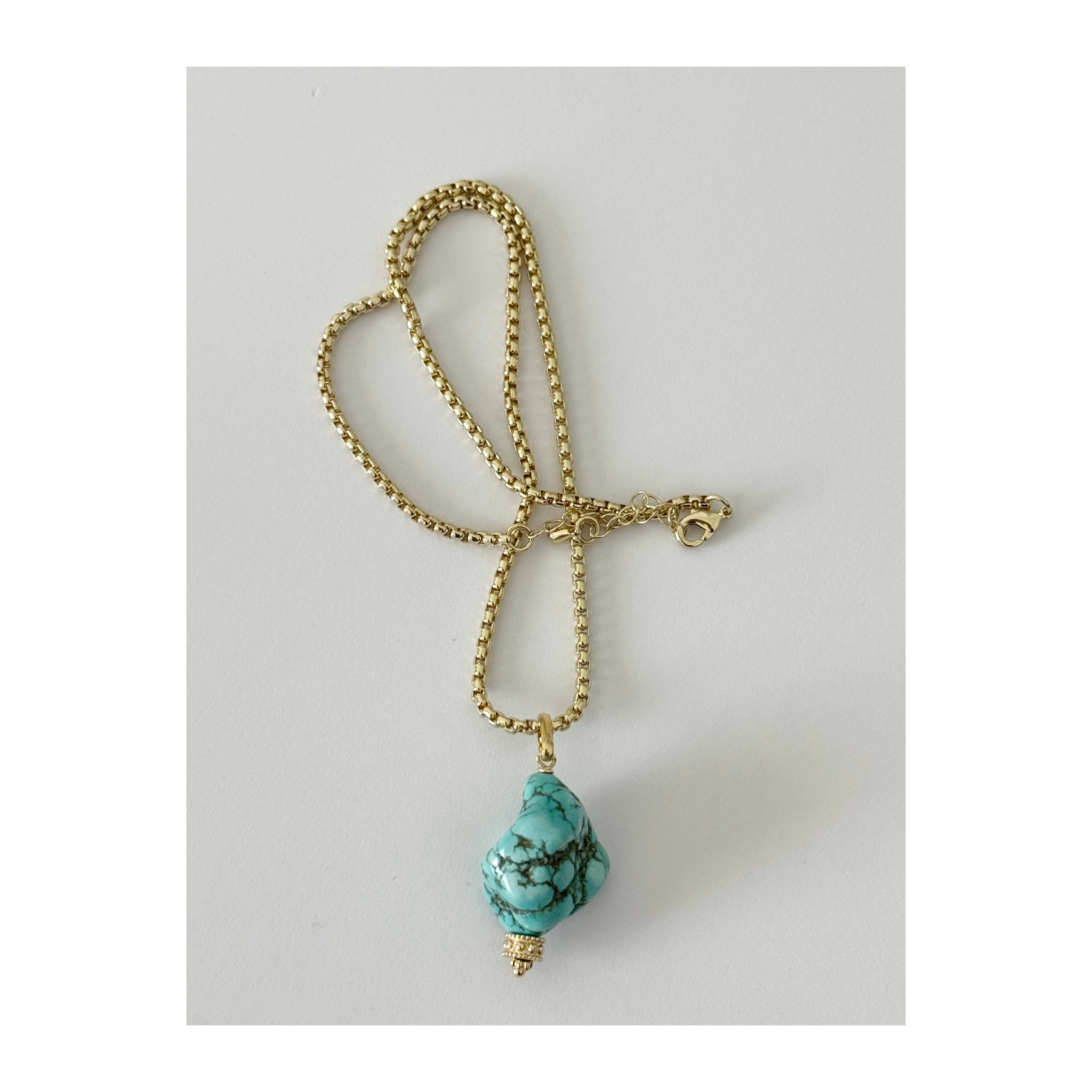 A gold beaded chain necklace with a teardrop-shaped turquoise stone pendant, displayed on a light gray background.