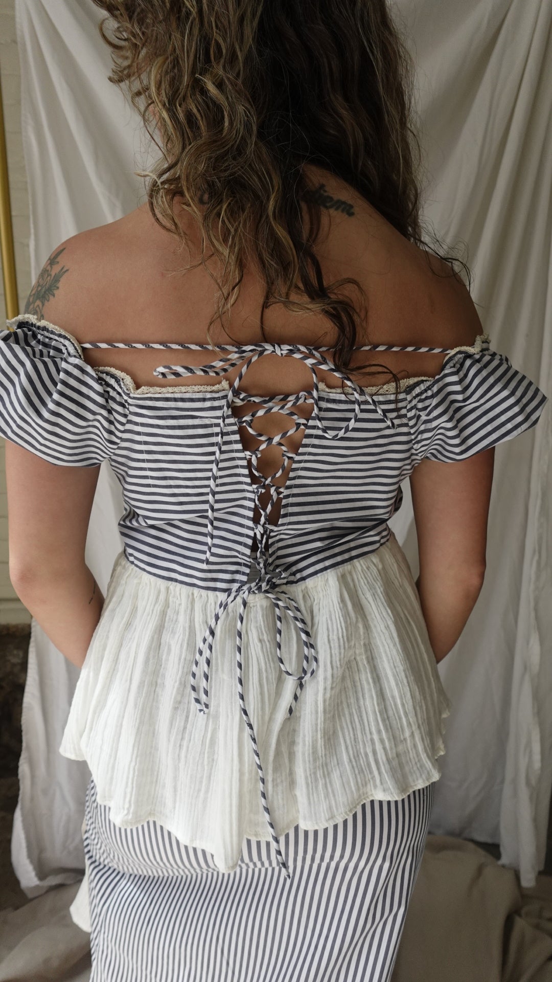 Person wearing a striped dress with a neutral background