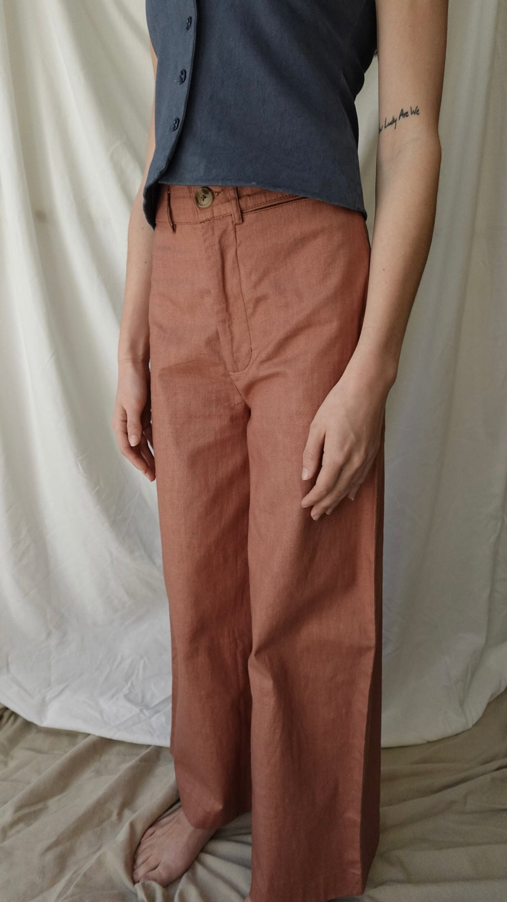 Person wearing a dark shirt and brown pants against a white background