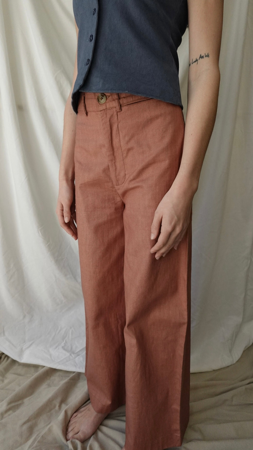 Person wearing a dark shirt and brown pants against a white background