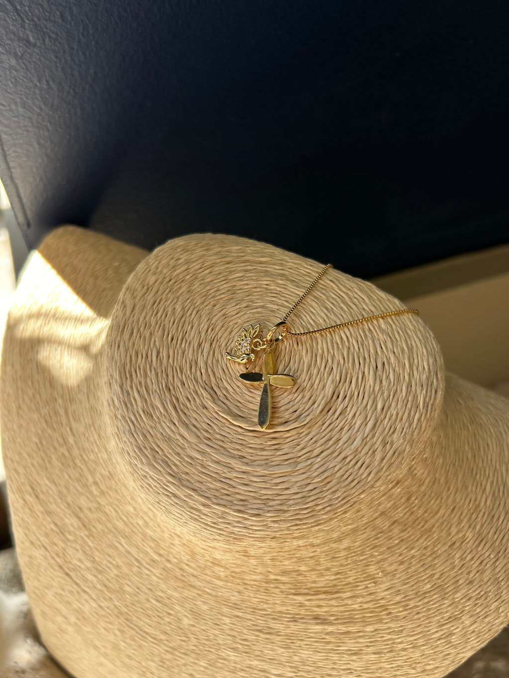 Gold necklace with a heart pendant on a mannequin head wrapped in beige yarn.