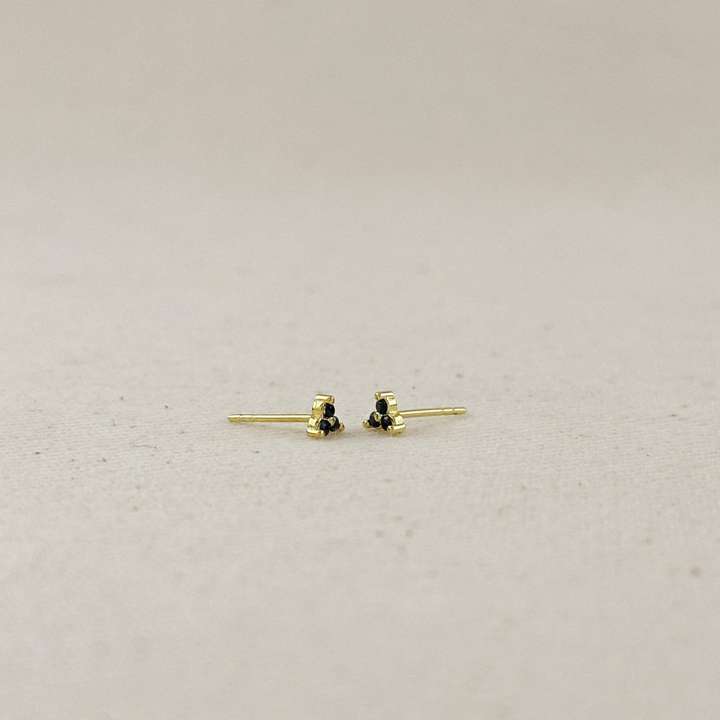 Gold earrings with black stones on a light gray background