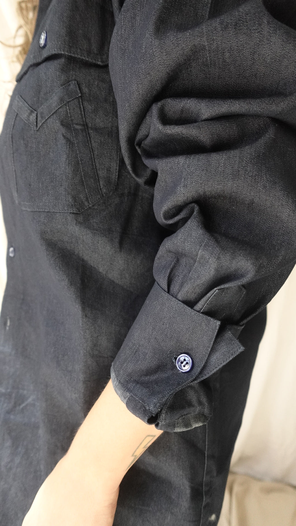 Close-up of a dark gray jacket with a button on a beige surface