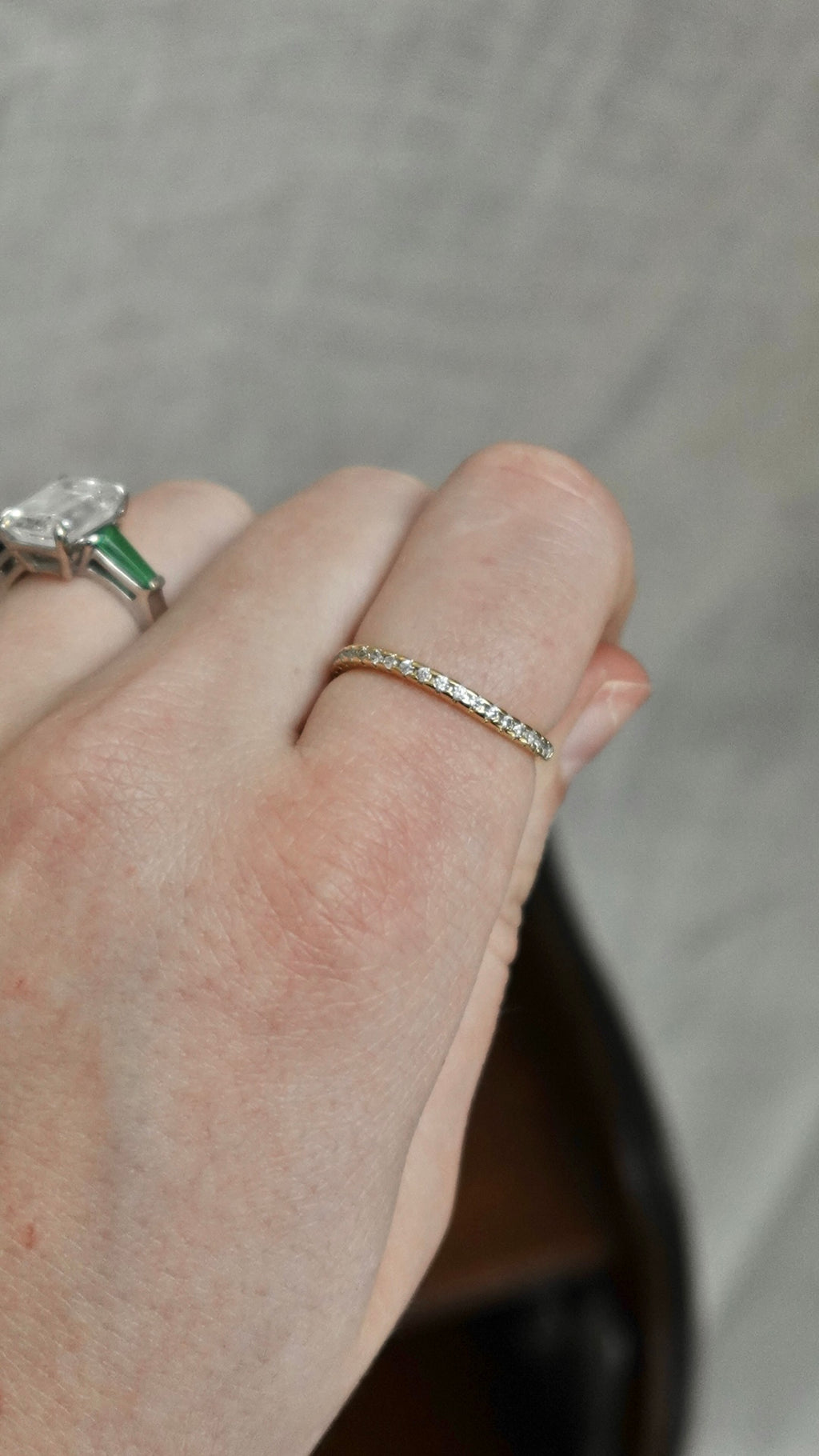 Close-up of a hand wearing two rings on a neutral background