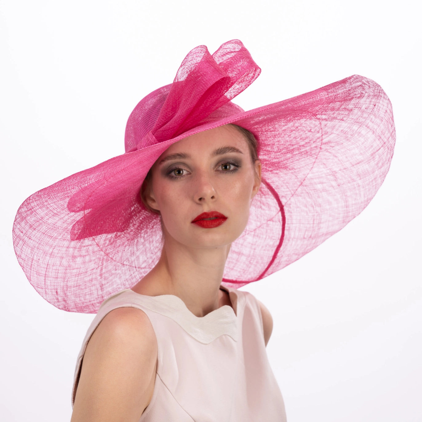 Woman wearing a large pink hat on a white background