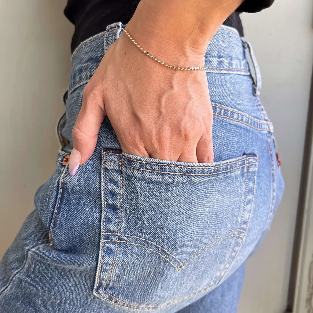 Person wearing blue jeans with a hand in the pocket against a neutral background