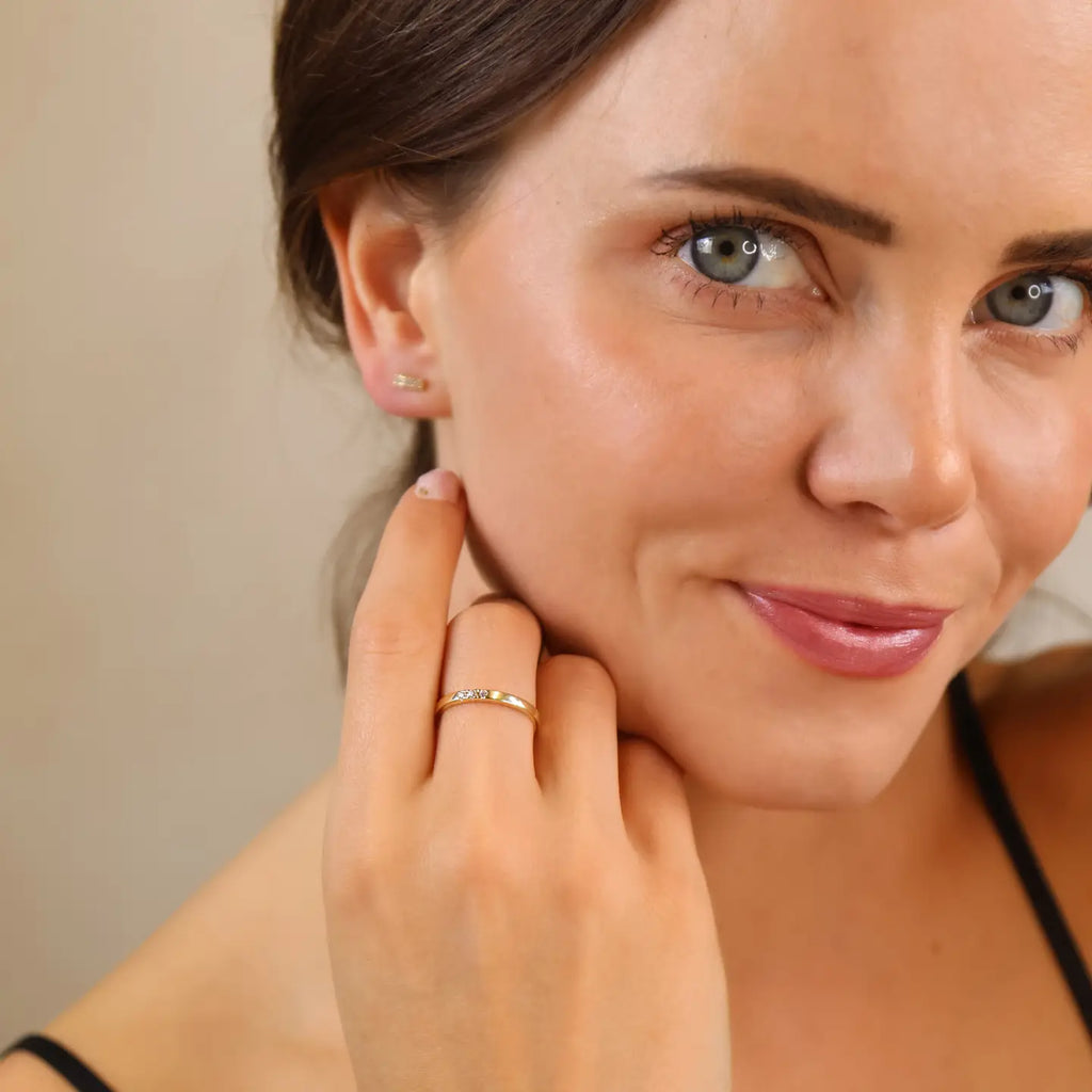 Woman wearing a gold earring and ring, looking to the side.