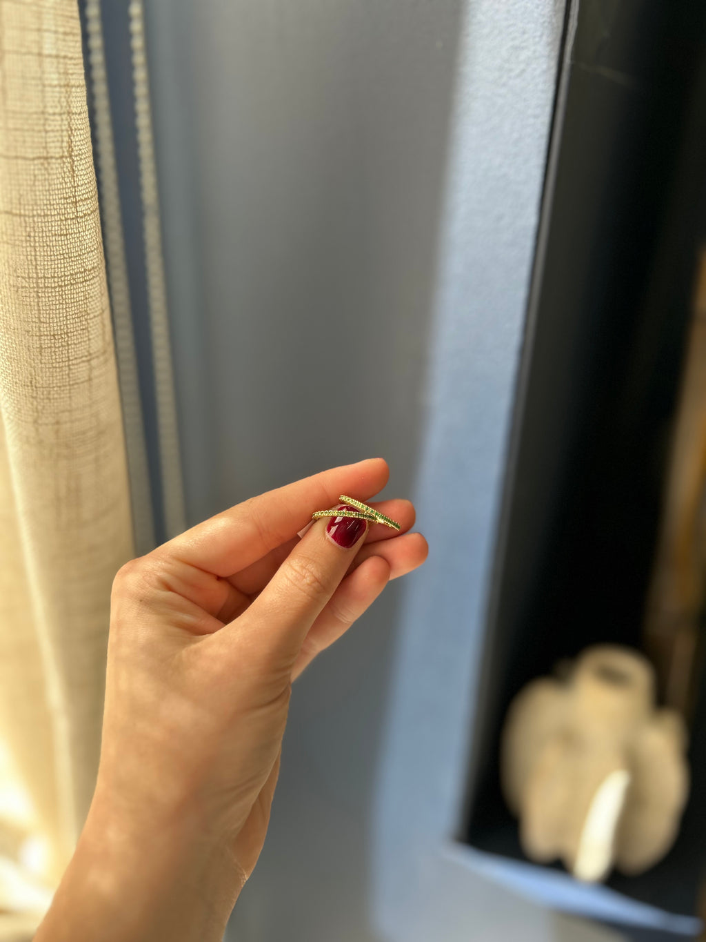Hand holding a small ring in front of a mirror with a blurred background