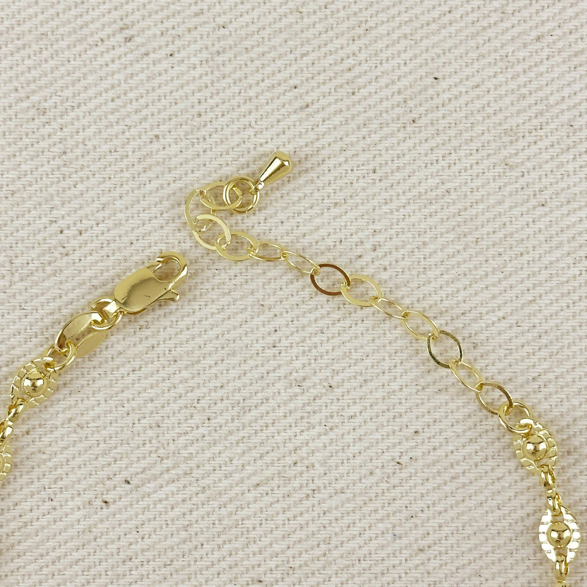 Gold bracelet with a clasp on a textured beige background