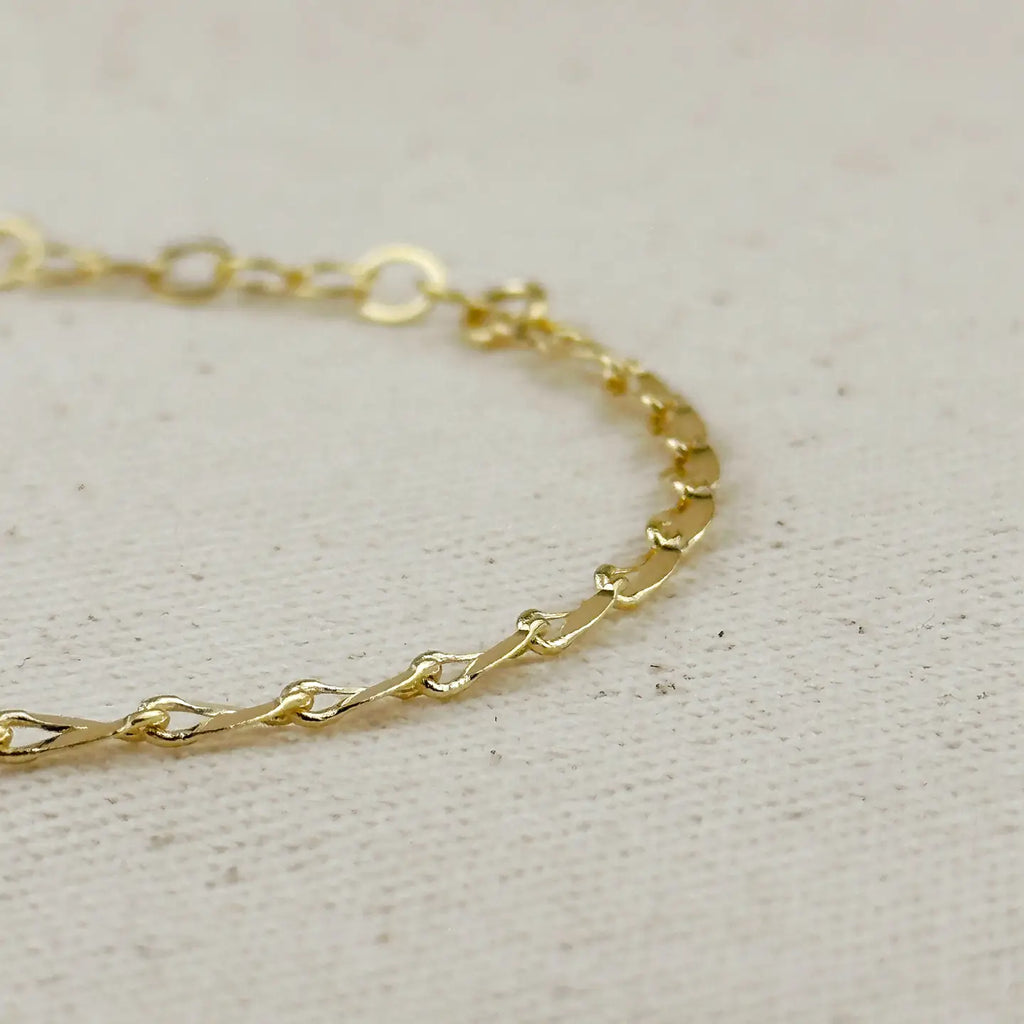 Gold chain bracelet on a light gray background
