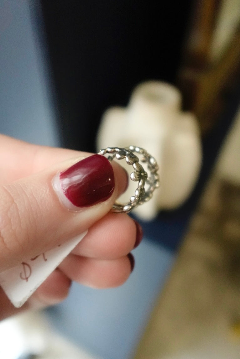 Hand holding a silver ring with a blurred background
