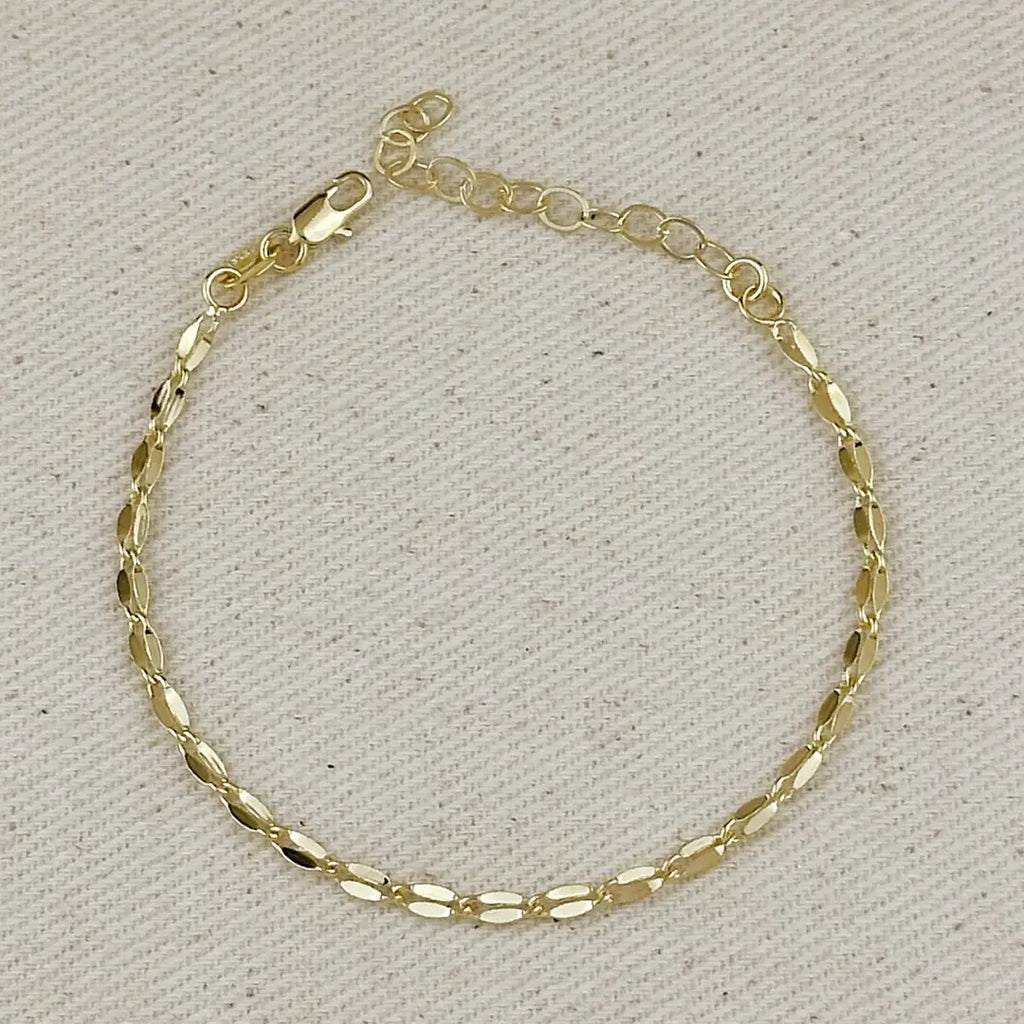 Gold bracelet on a textured beige background