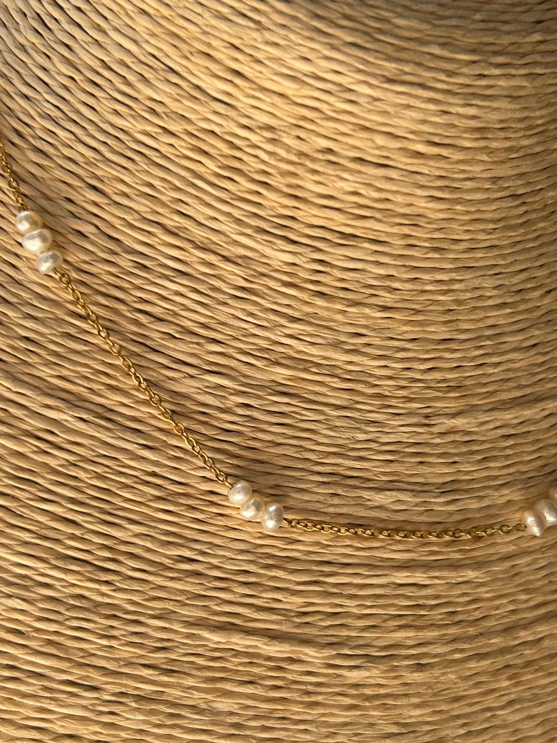 Gold necklace with pearls on a textured beige background