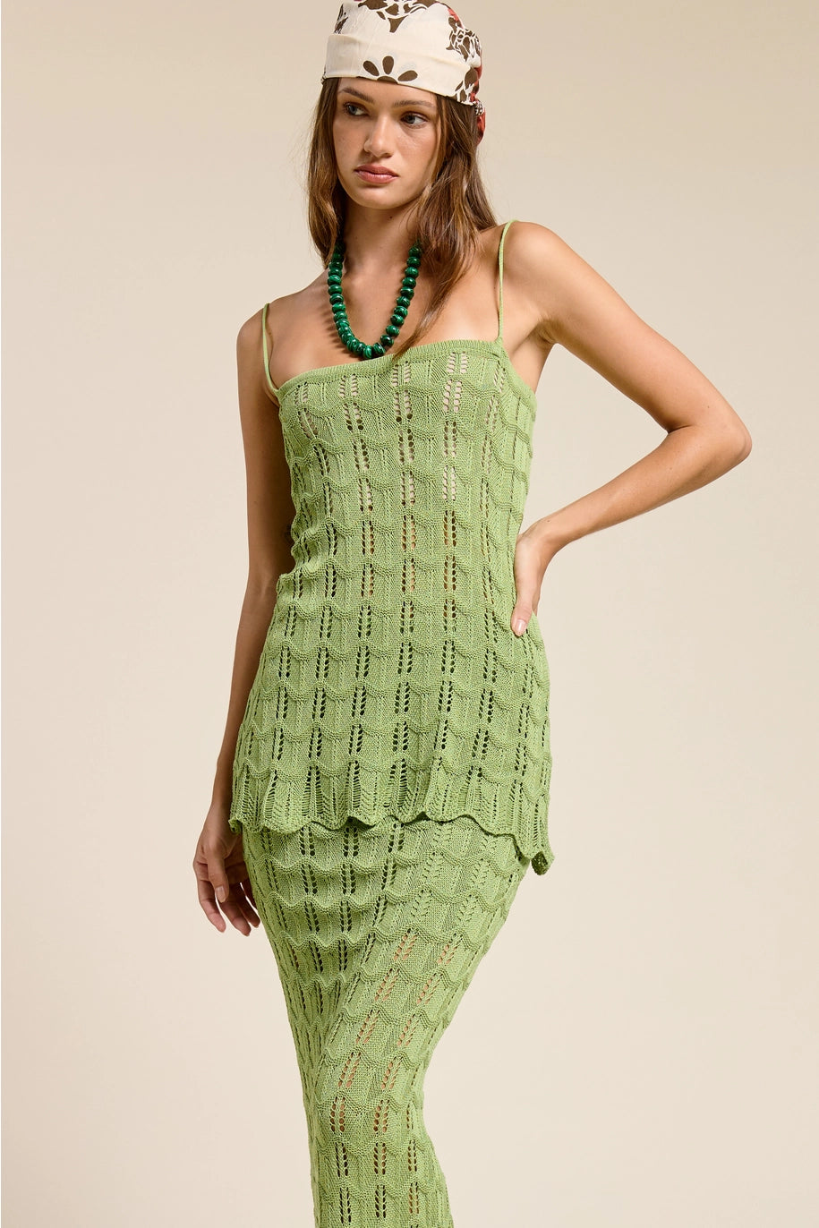 Woman wearing a green crochet dress with a neutral background