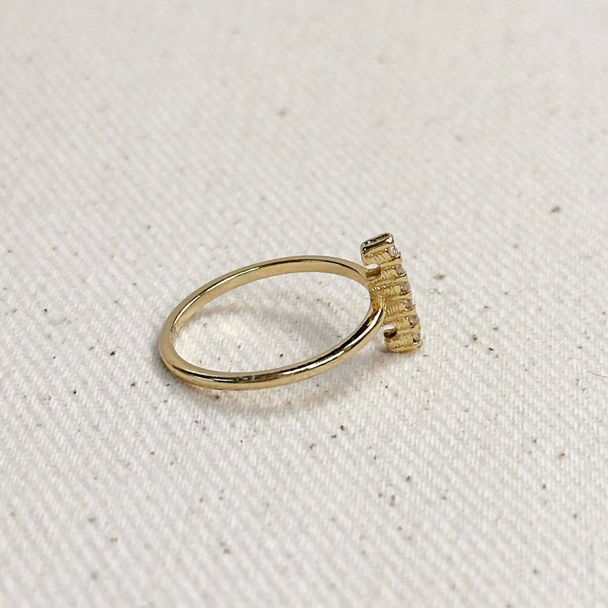Gold ring with a textured band on a light beige fabric background