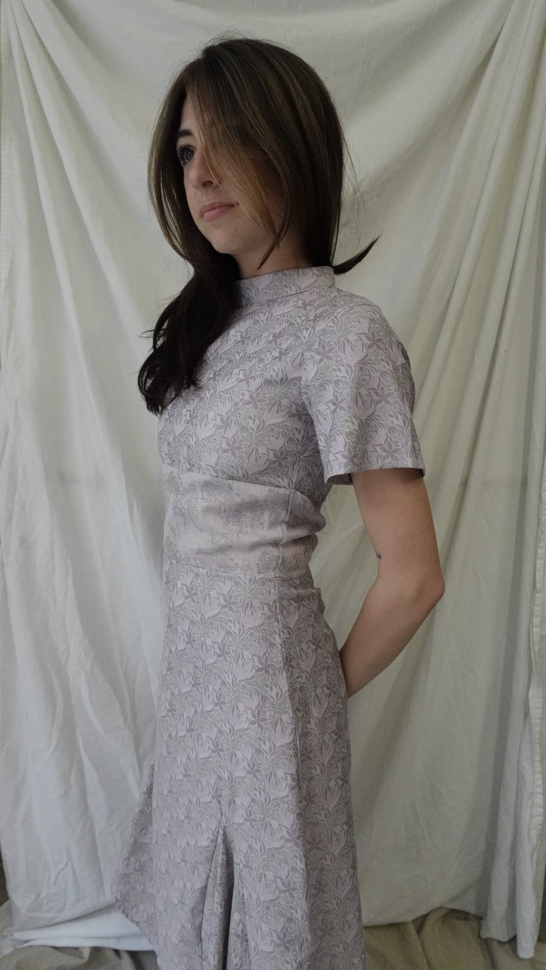 Woman wearing a long, light-colored dress against a neutral background