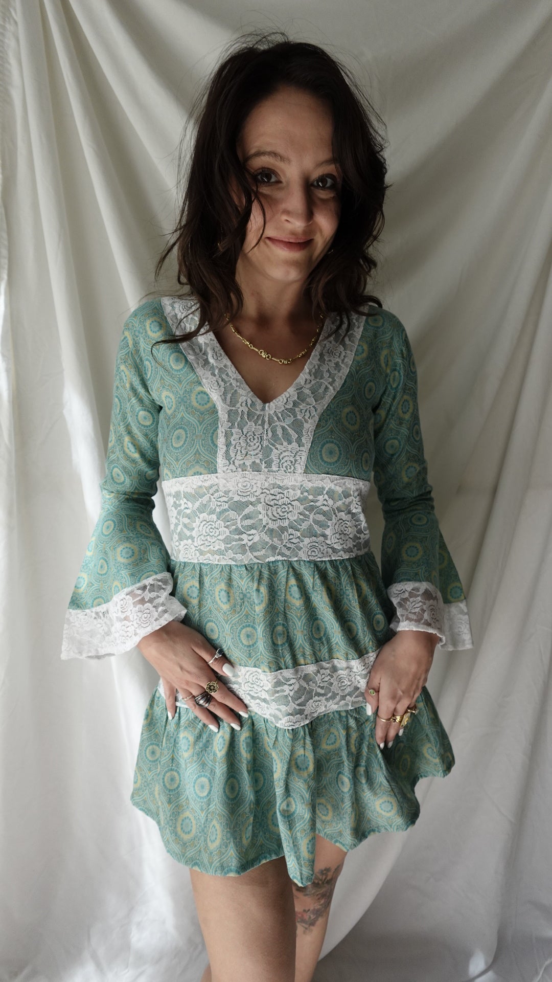 Woman wearing a green dress with lace details on a white background
