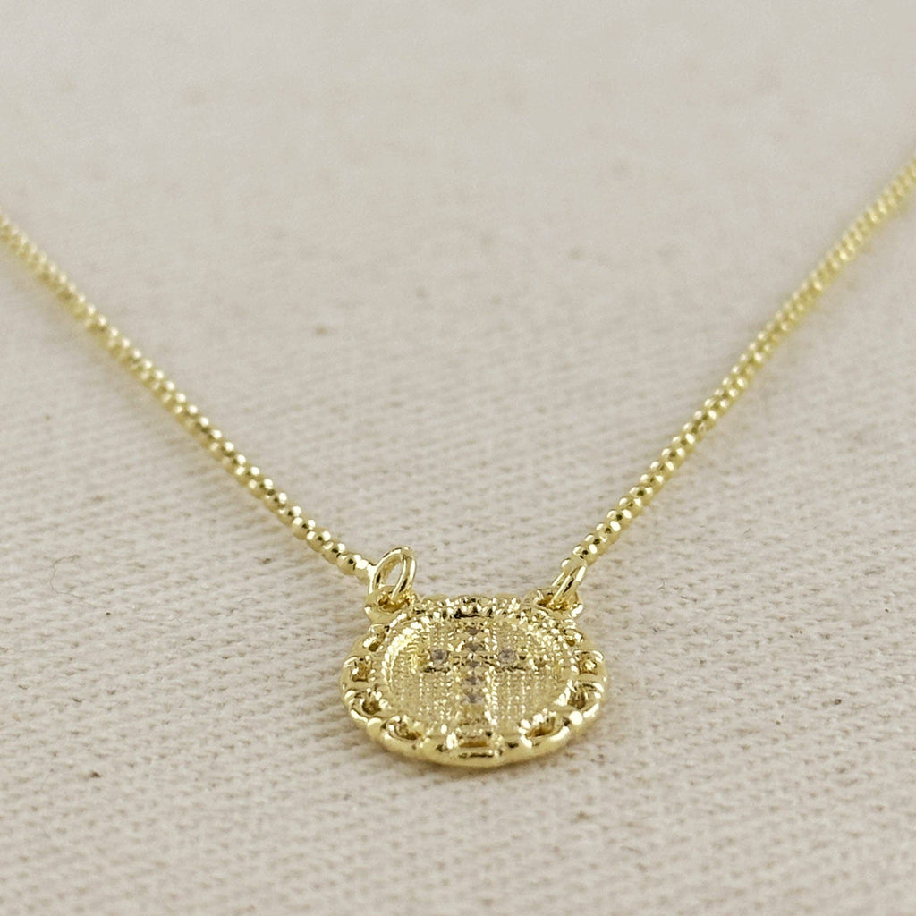 Gold necklace with a circular pendant on a light gray background