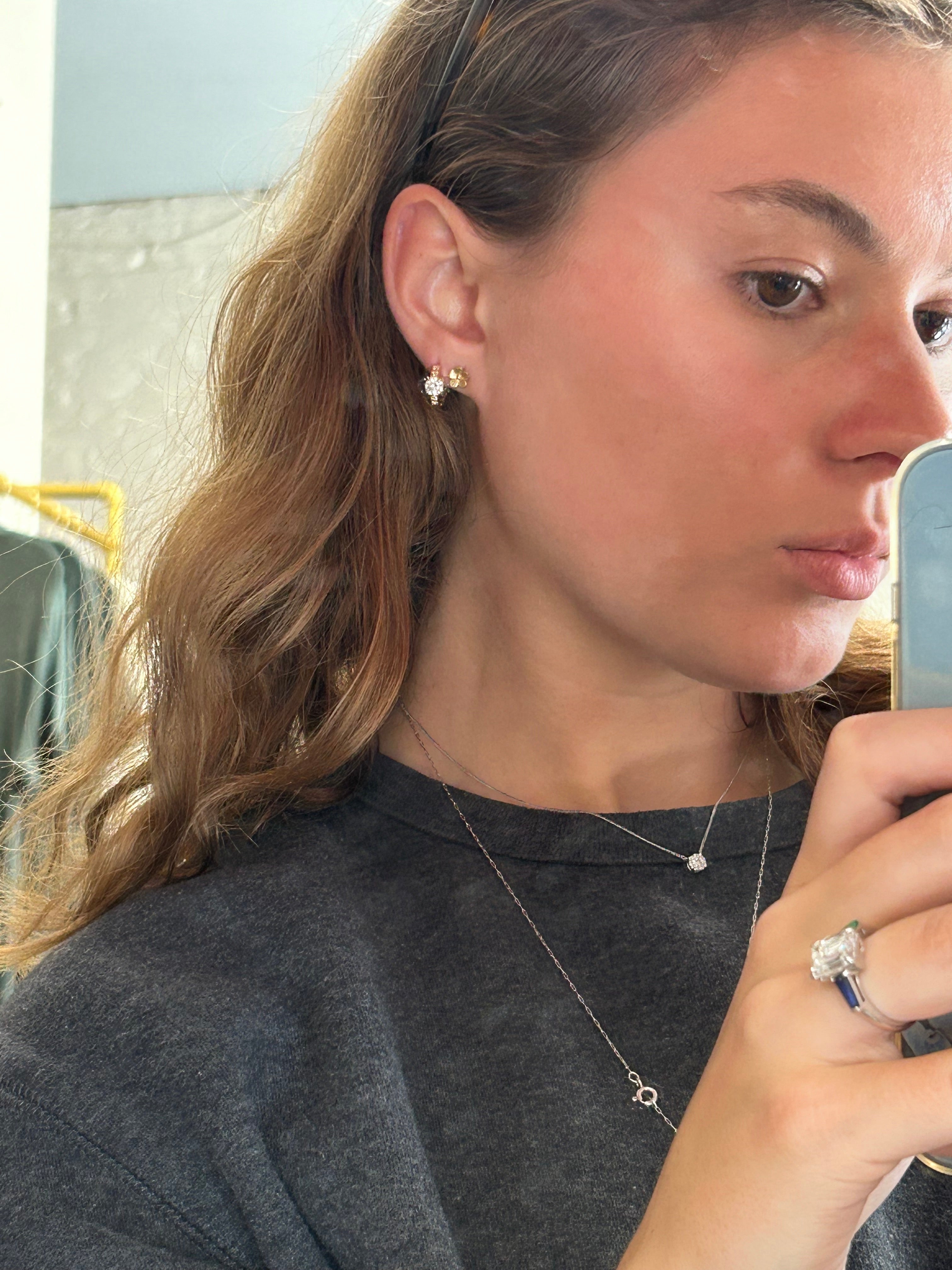 Woman taking a mirror selfie wearing a gray sweater and diamond ring.