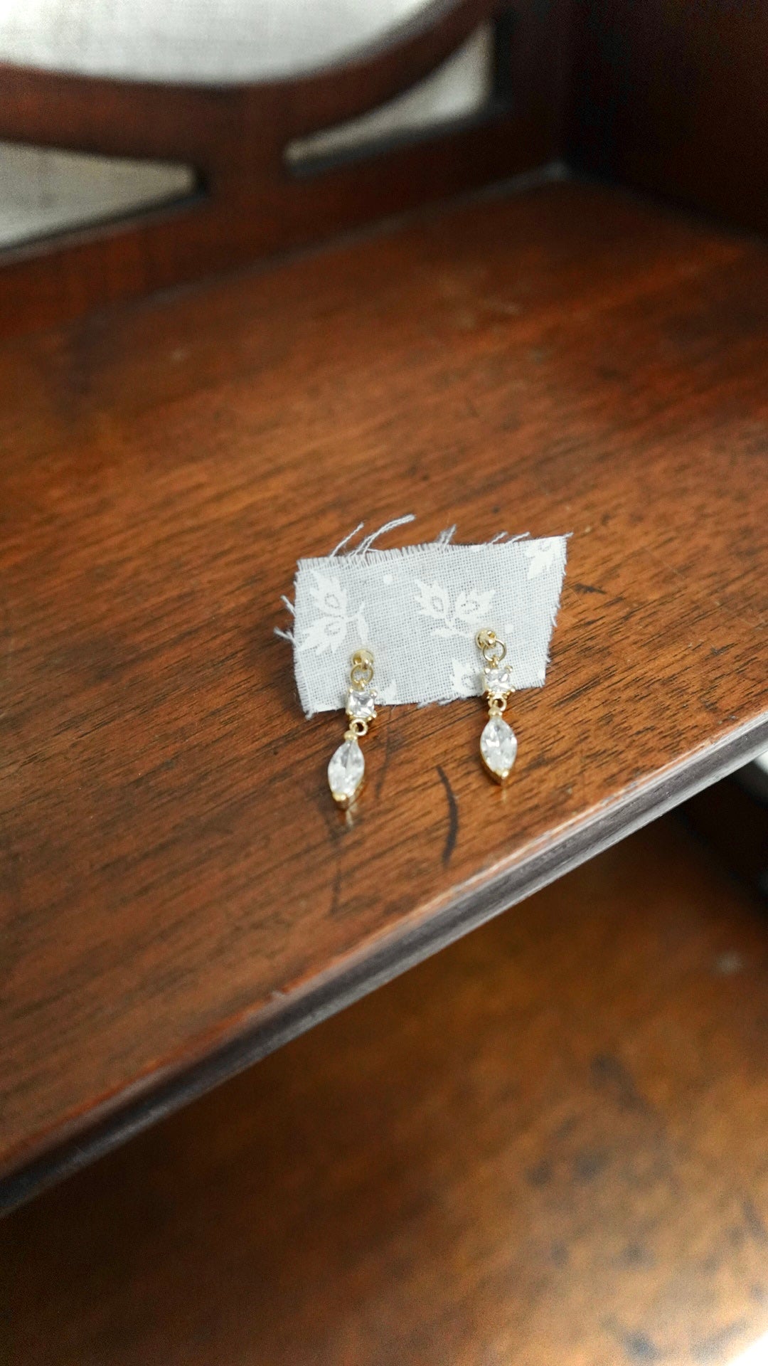 Gold earrings on a white card with a wooden surface background