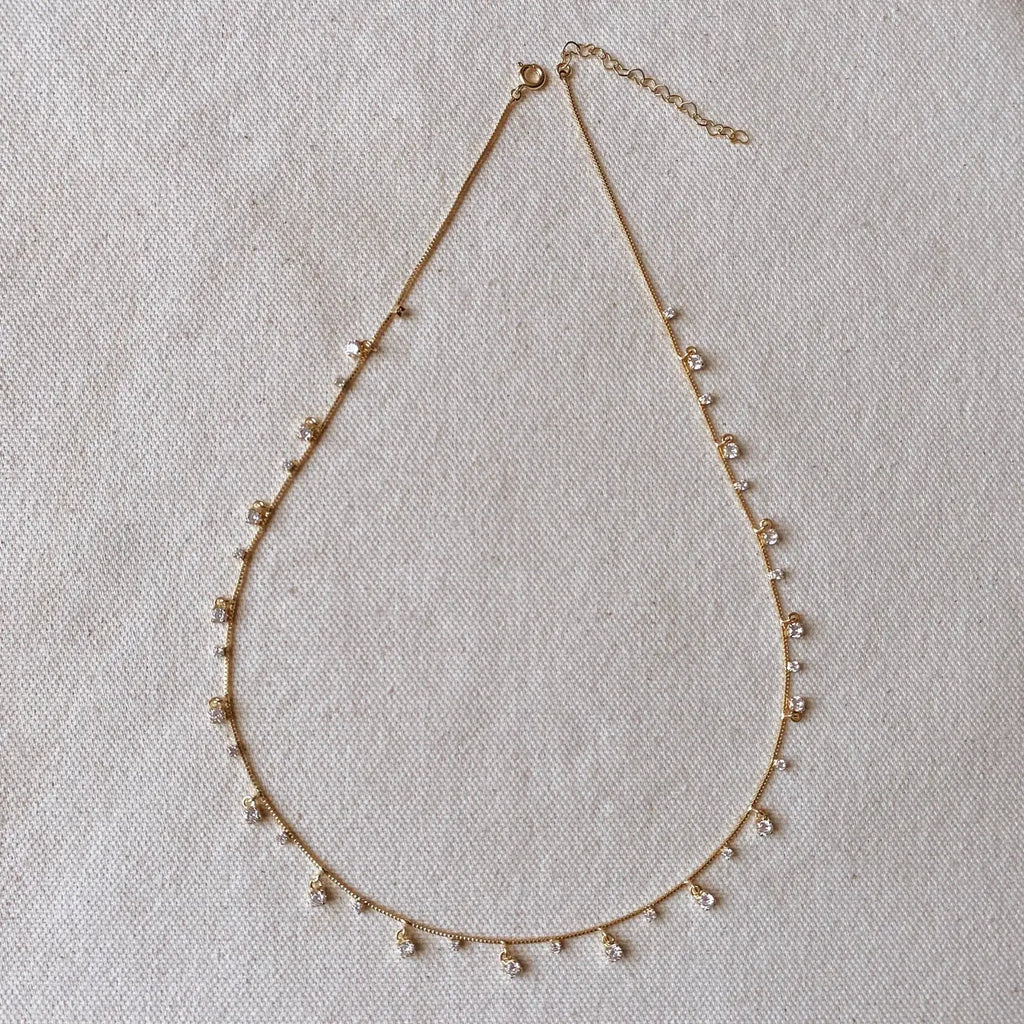 Delicate gold necklace with small beads on a light fabric background