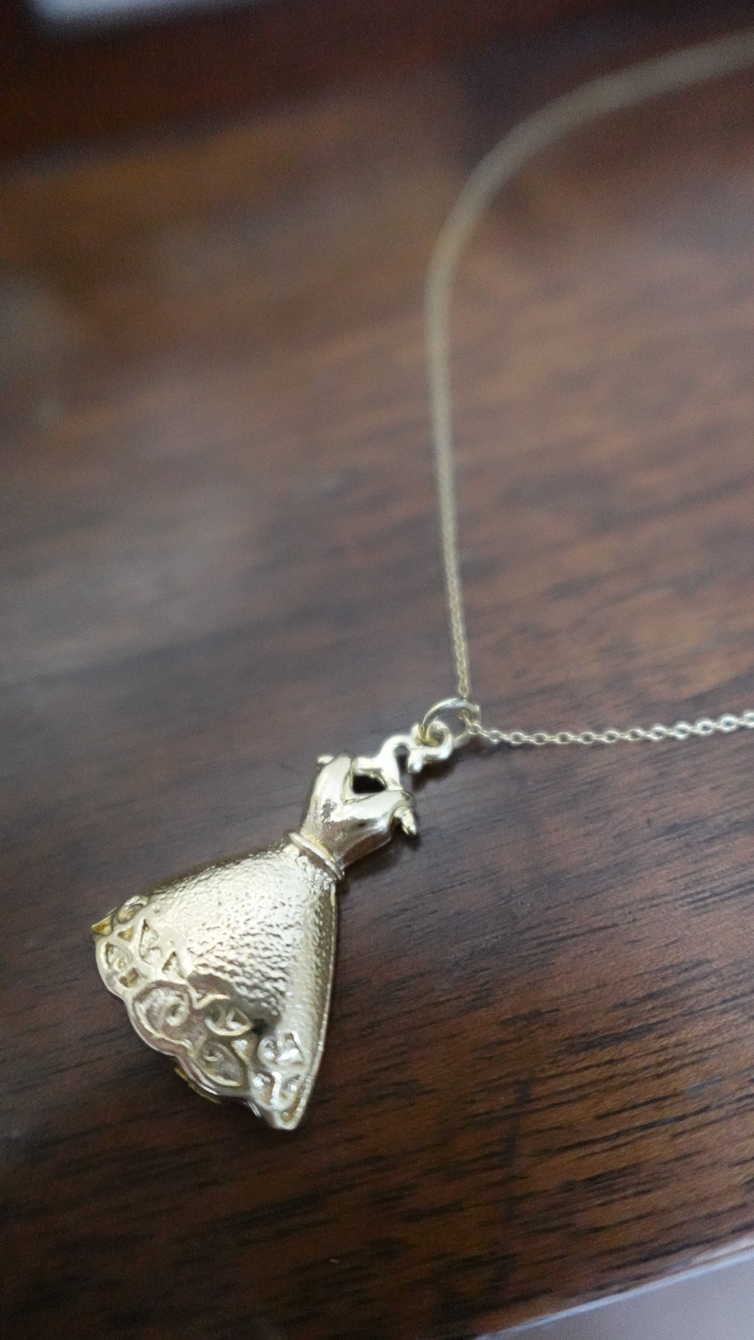 Gold necklace with a decorative pendant on a wooden surface