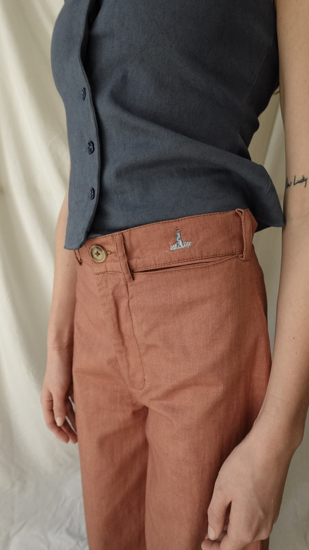 Close-up of a person wearing a dark shirt and brown pants with a visible brand logo.