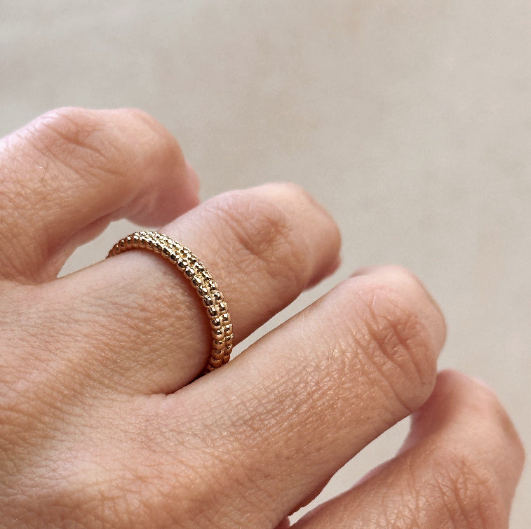 Gold ring on a finger against a neutral background