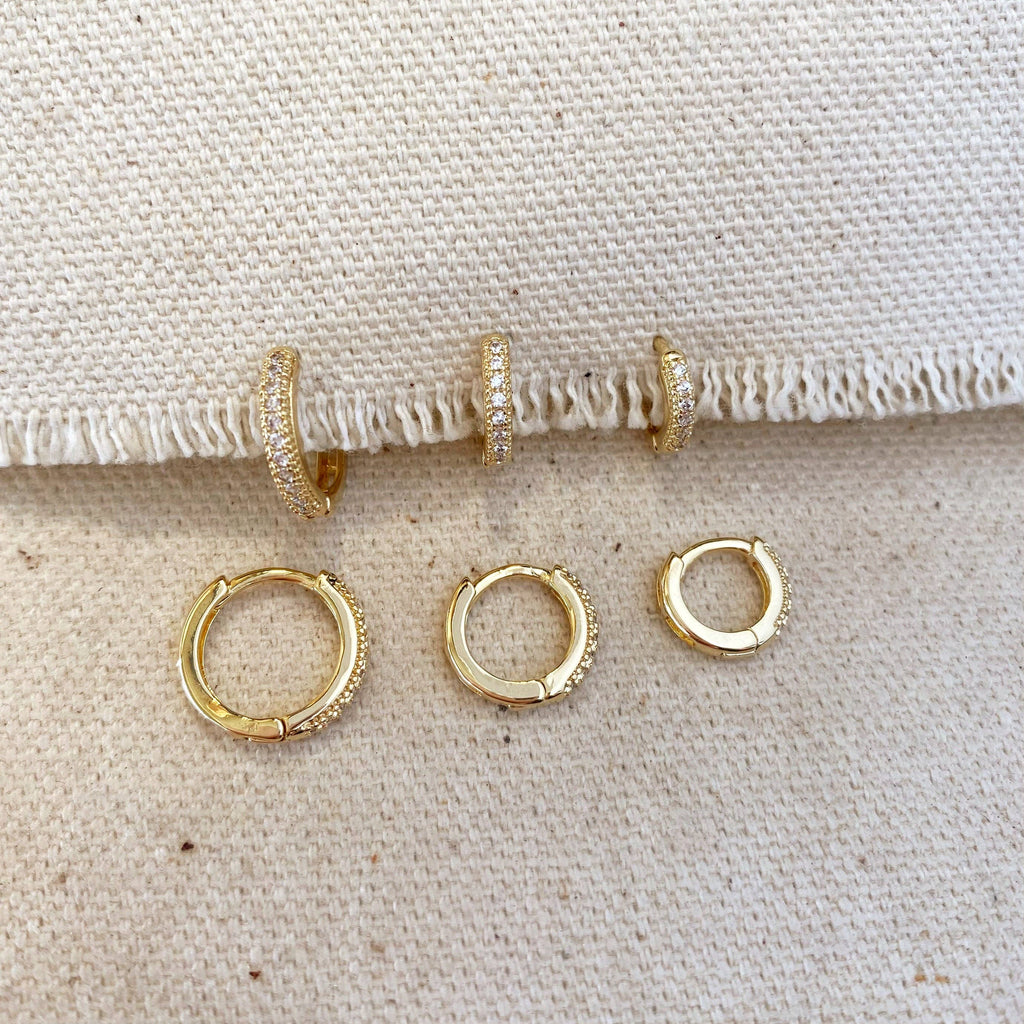 Set of gold hoop earrings on a textured beige surface