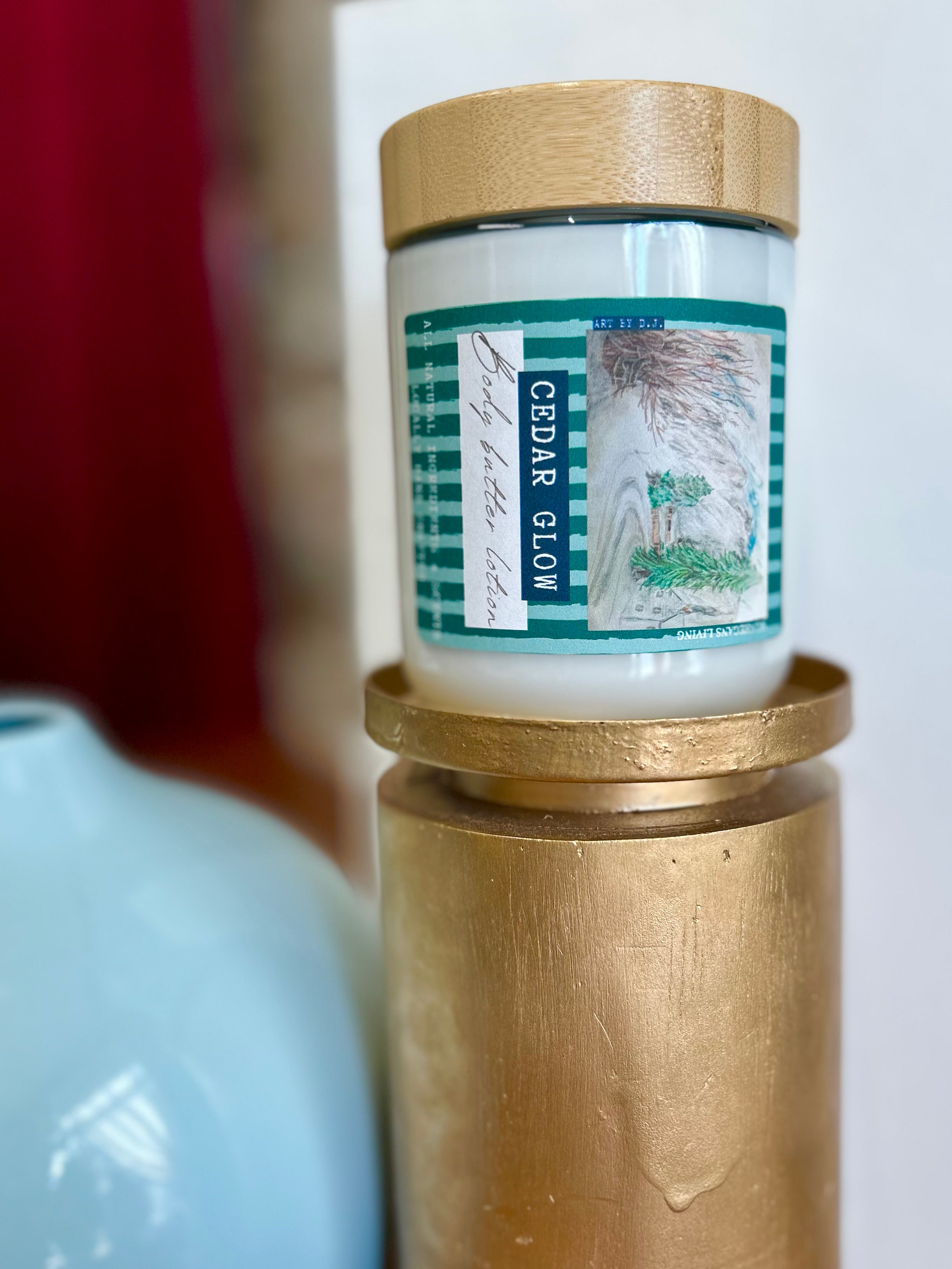 Candle in a glass jar with a wooden lid on a brass stand against a blurred background