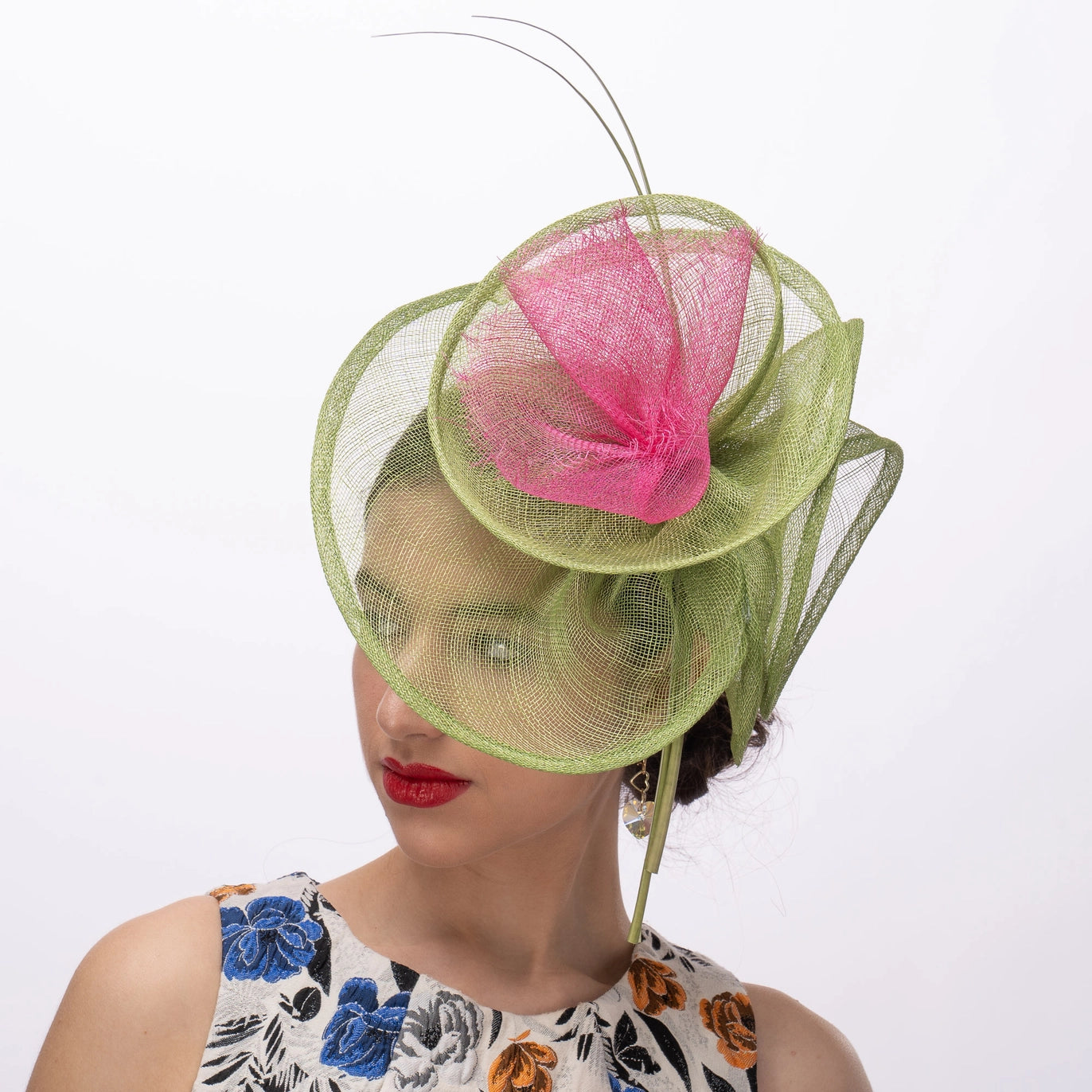 Woman wearing a green and pink decorative hat on a white background
