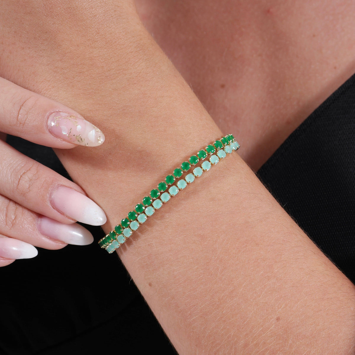 Close-up of a wrist wearing a green beaded bracelet with a black background