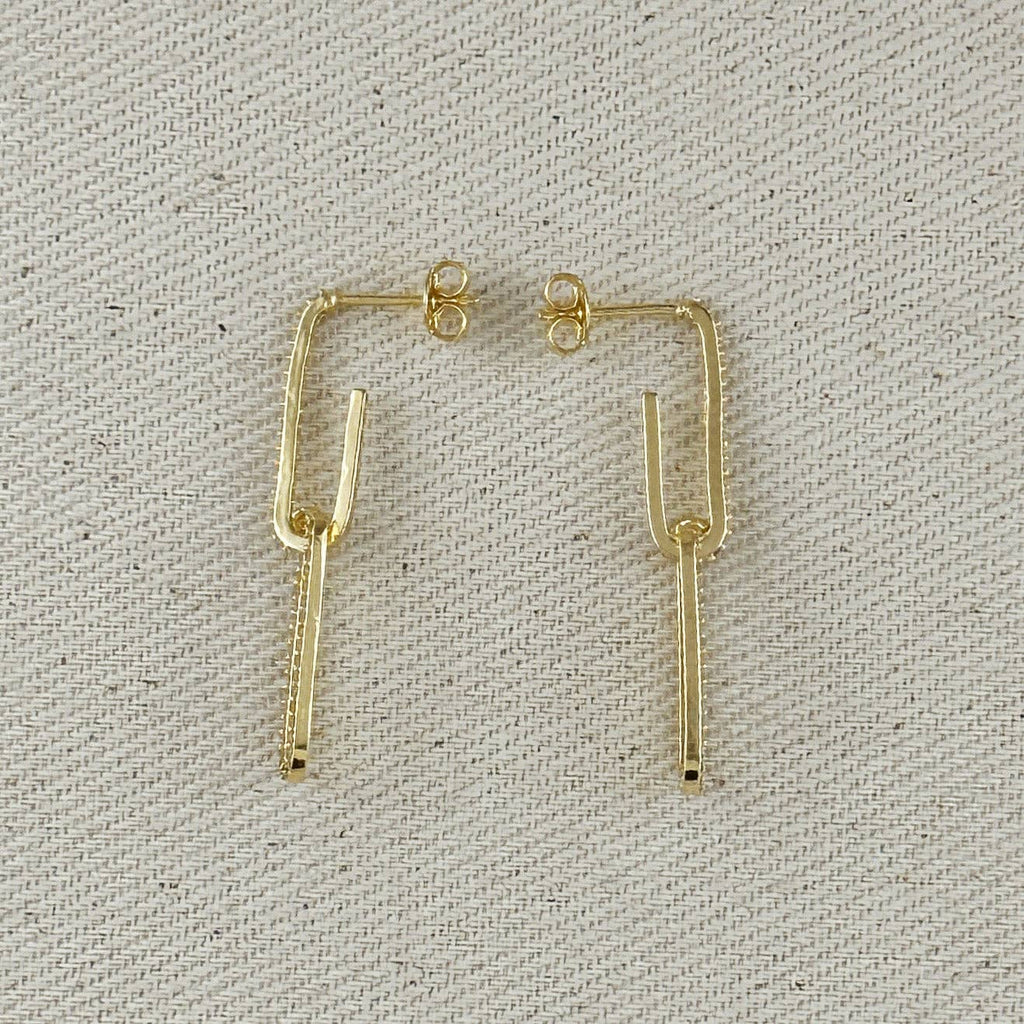 Gold earrings on a textured gray background