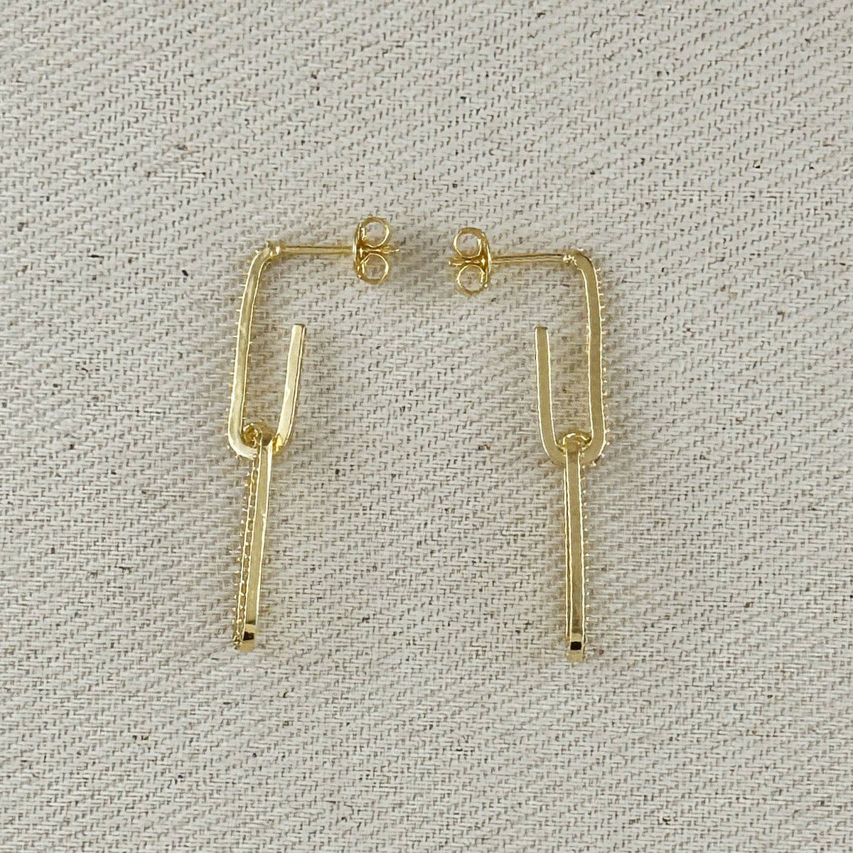 Gold earrings on a textured gray background