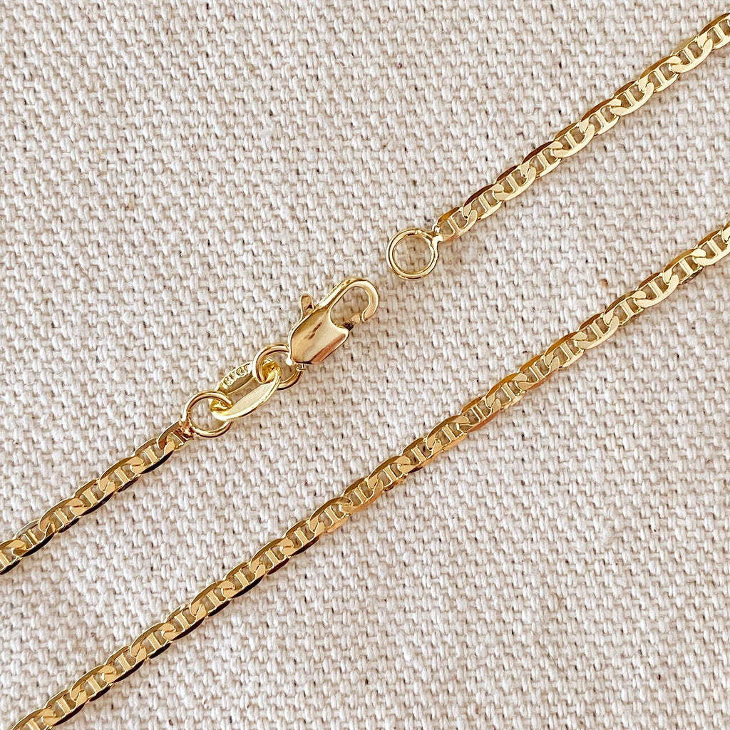 Gold chain necklace on a textured beige background