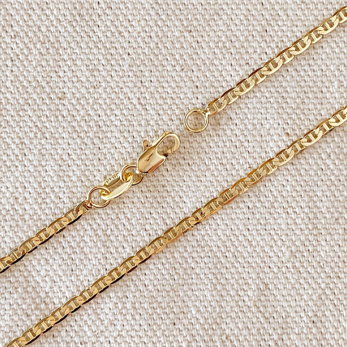 Gold chain necklace on a textured beige background