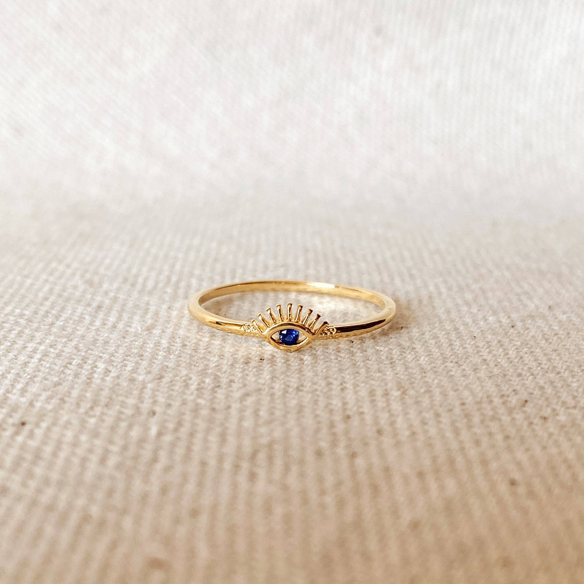 Gold ring with a blue gemstone on a beige fabric background