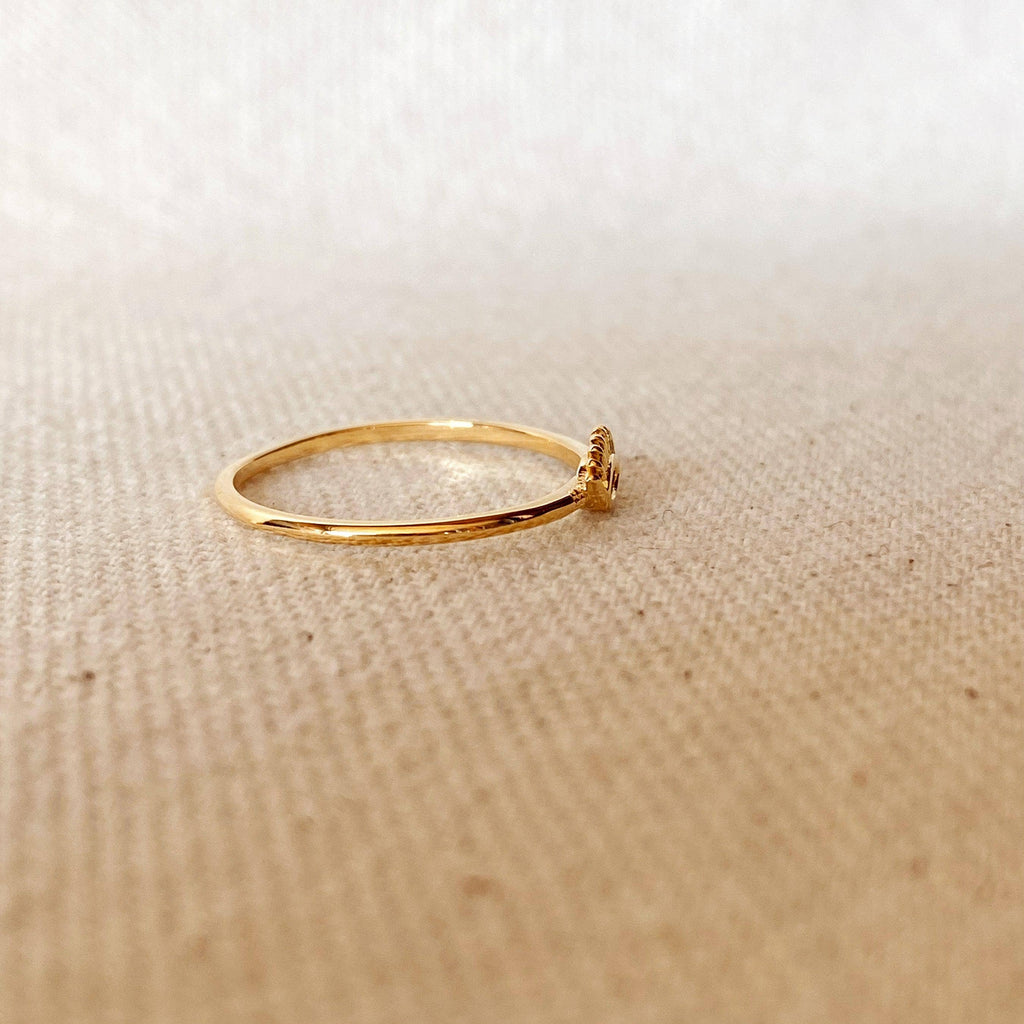 Gold ring with a small decorative element on a beige fabric background