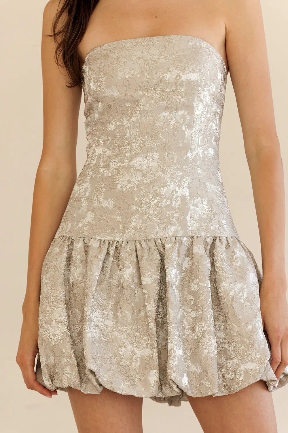 Woman wearing a strapless floral dress against a beige background