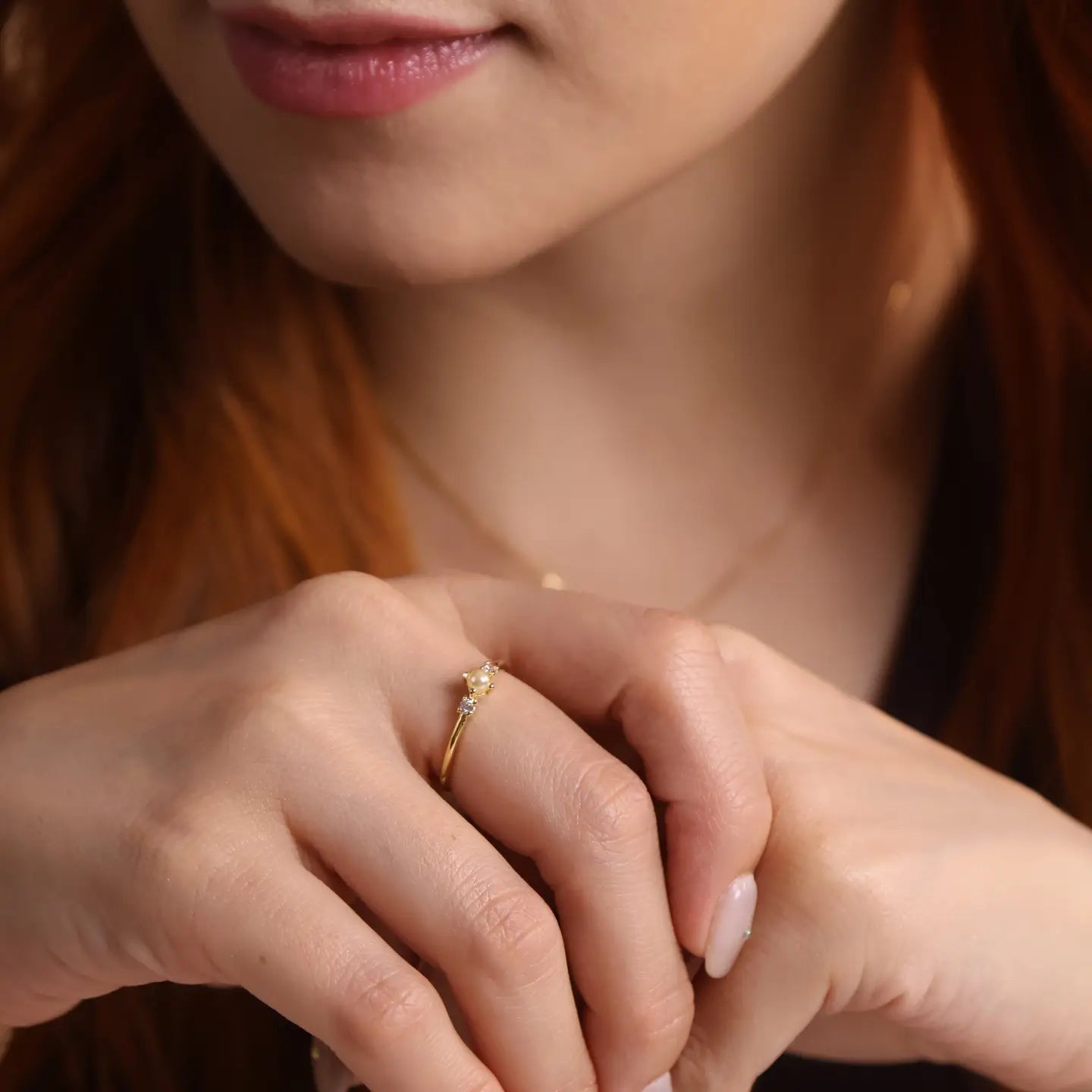 Close-up of a person's hands with a gold ring on a blurred background