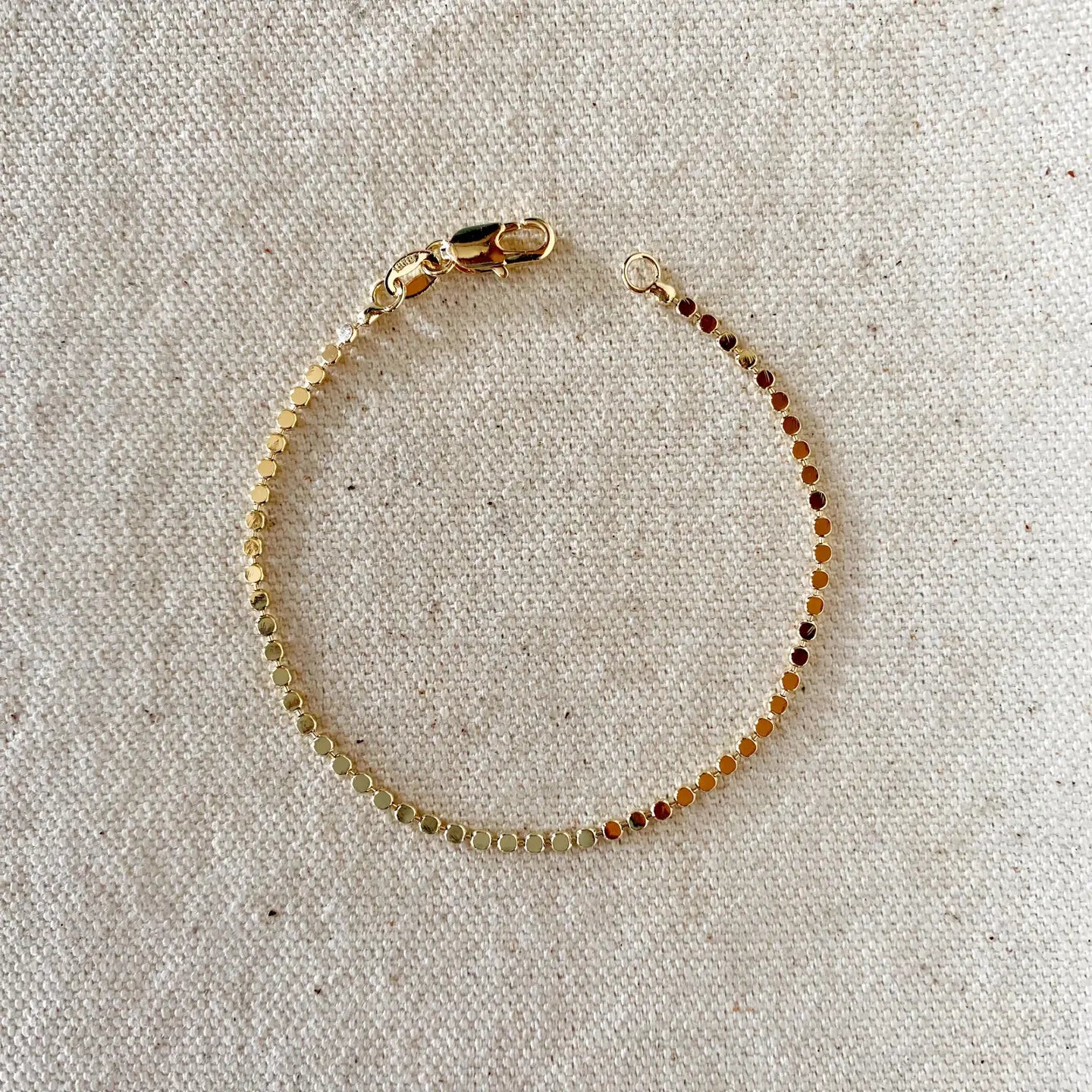 Beaded bracelet with gold clasp on a textured beige background