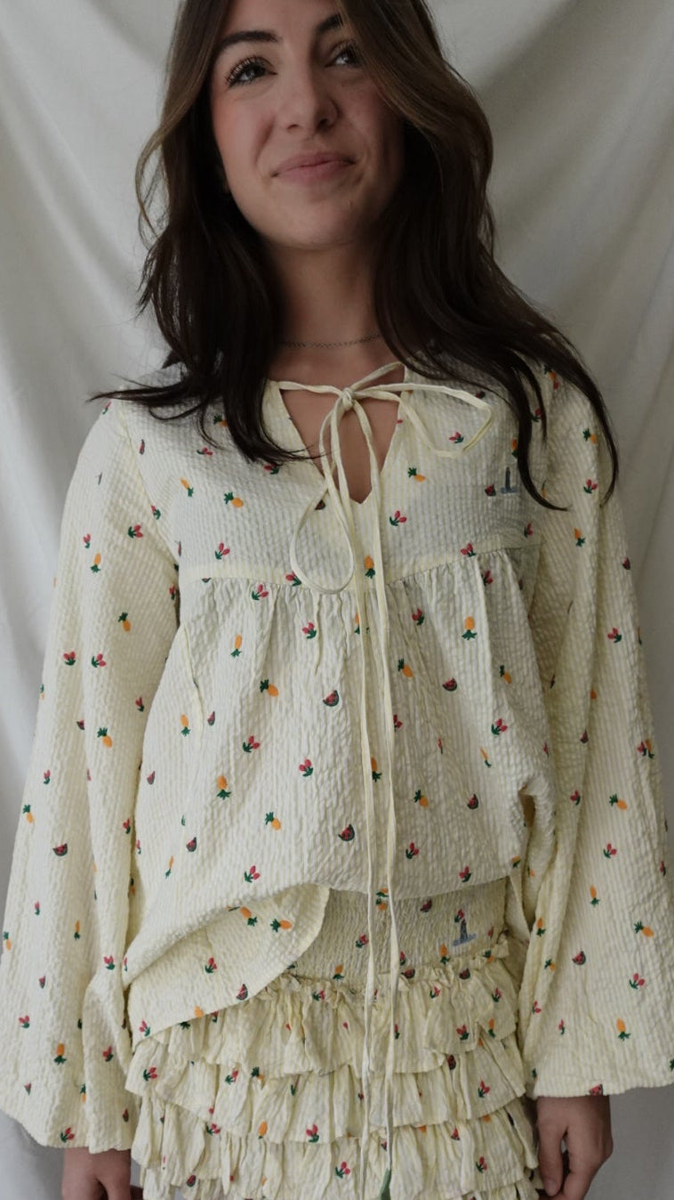 Woman holding a cream-colored dress with floral patterns against a white background