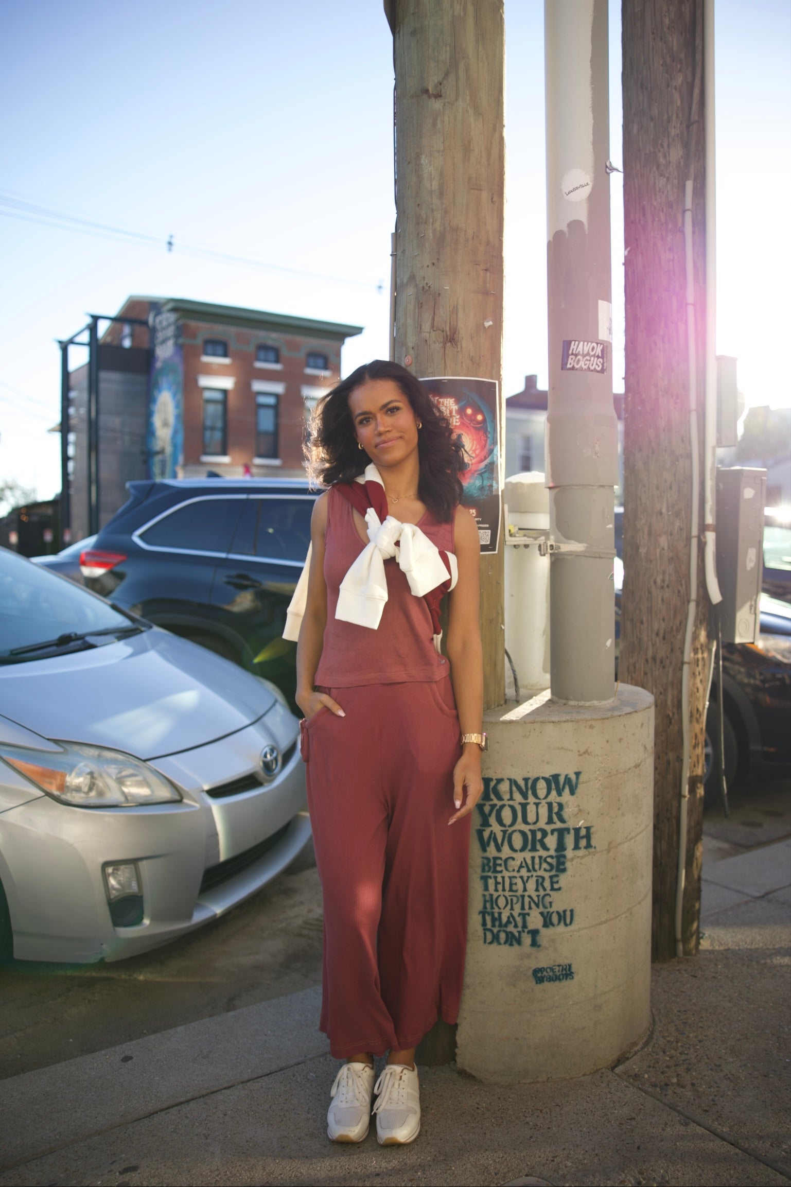 Woman standing on a city street with cars and a sign in the background
