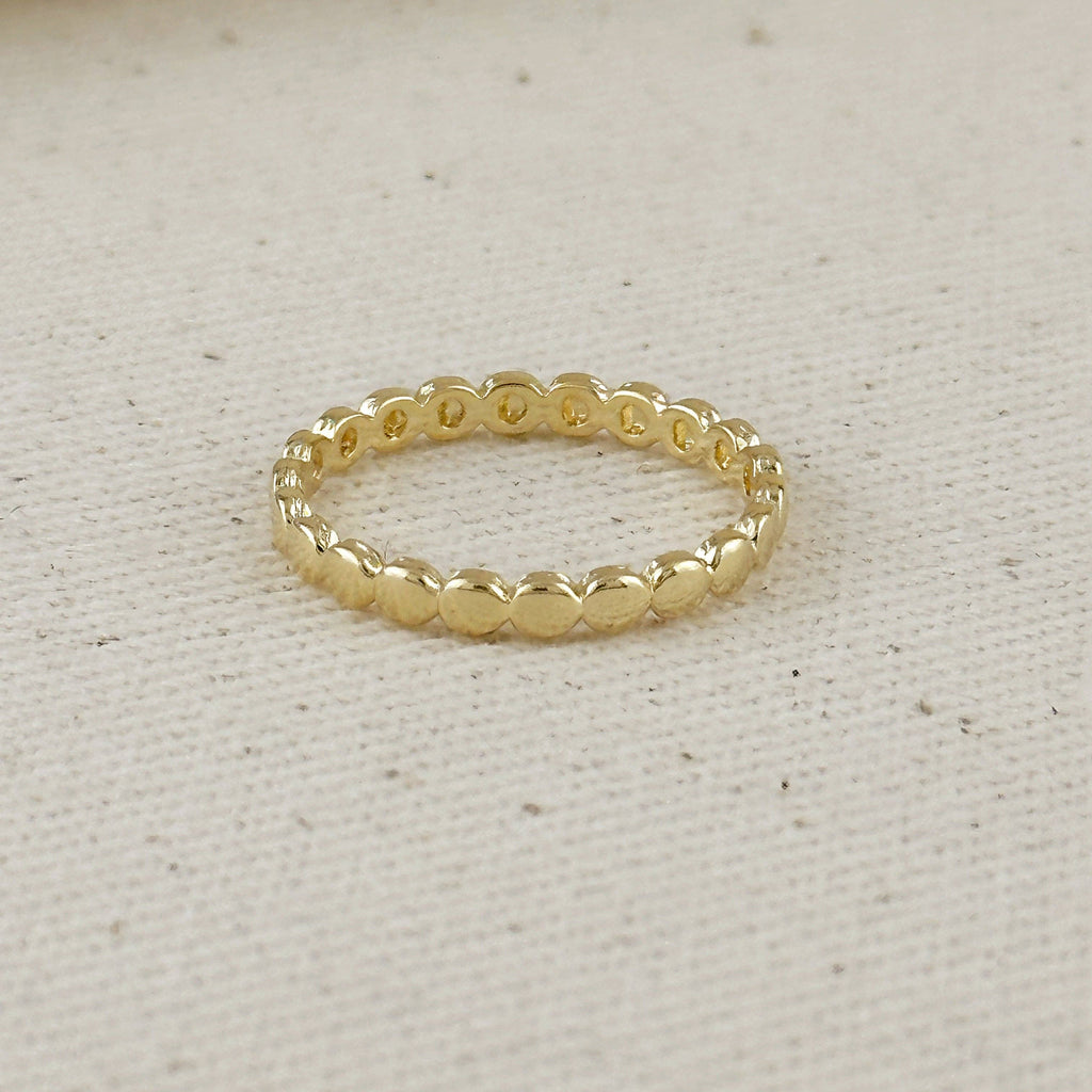 Gold beaded ring on a light beige fabric background